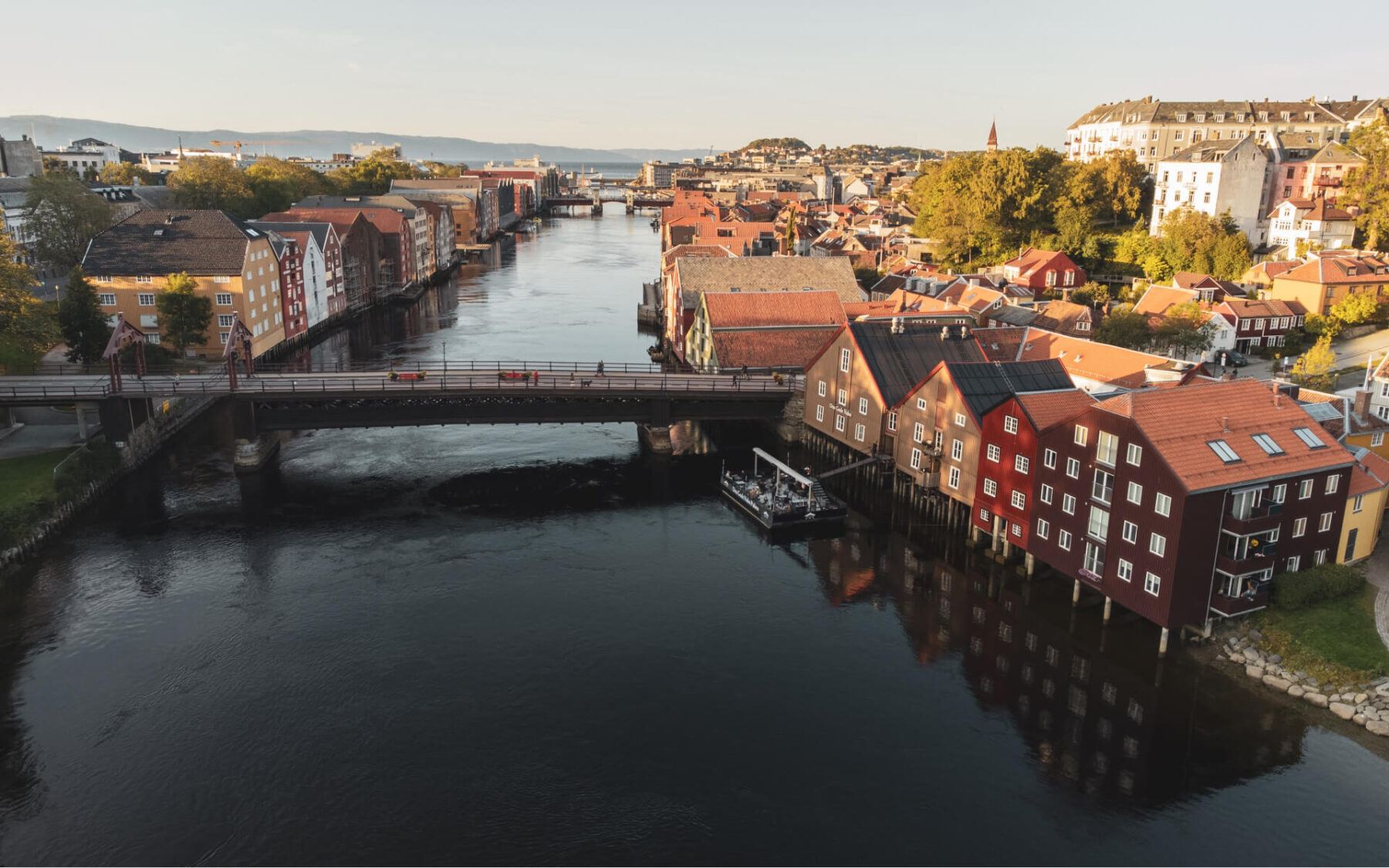Bilde av en elv i Trondheim med en bro over og byen på begge sider